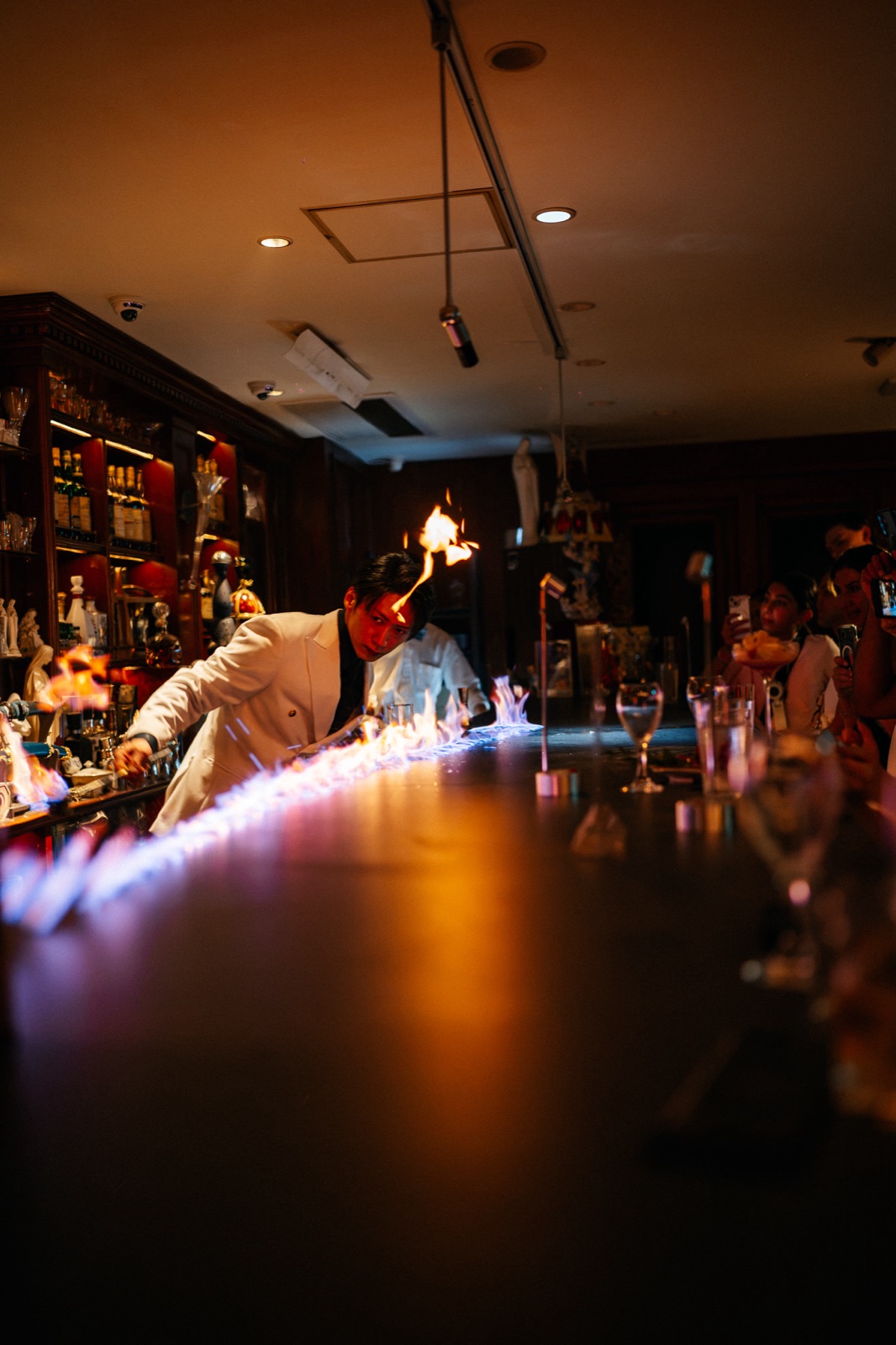 A bartender lighting a line of flame the length of the counter