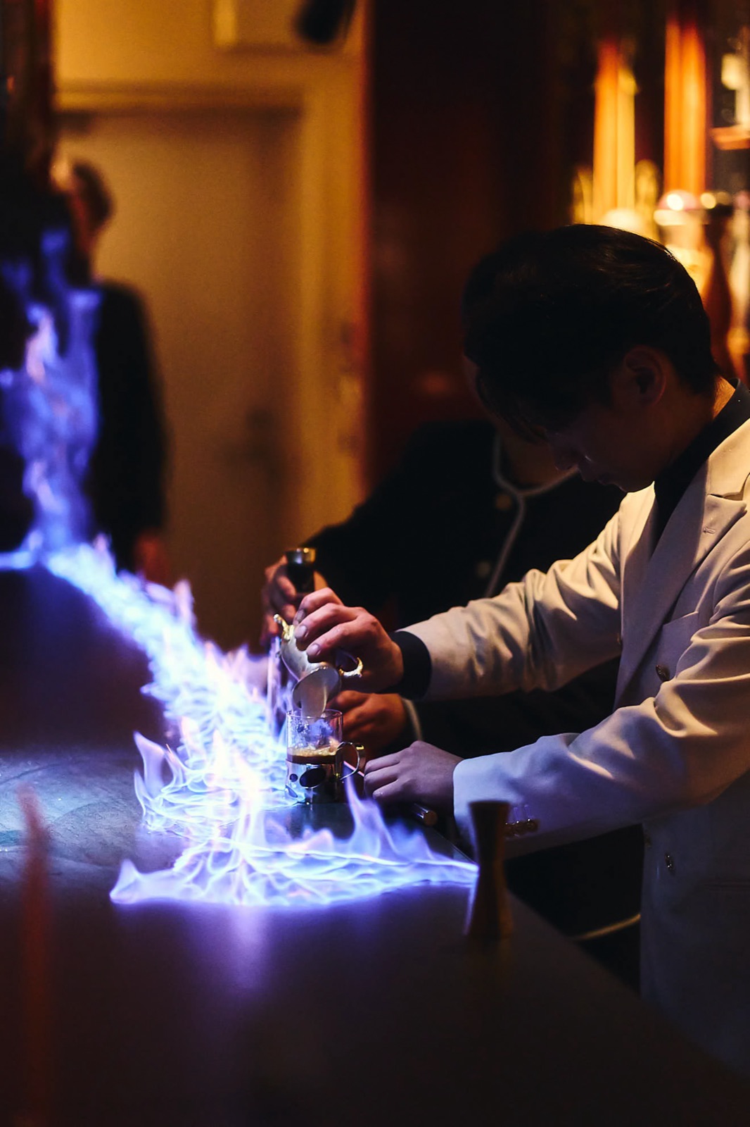 A drink built over blue flame at the counter