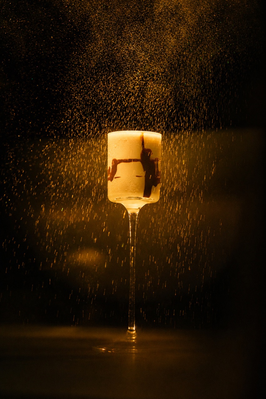 A stemmed glass lit gold against a fall of spray