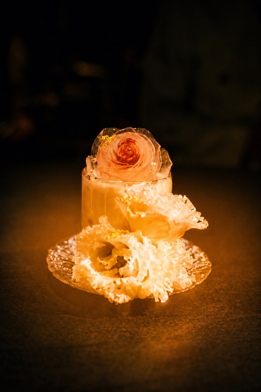 A rock glass capped with a carved rose of ice
