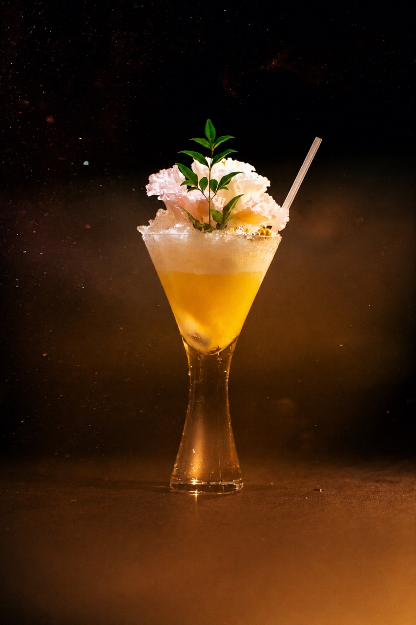 A cocktail crowned with crushed ice and a pale carnation